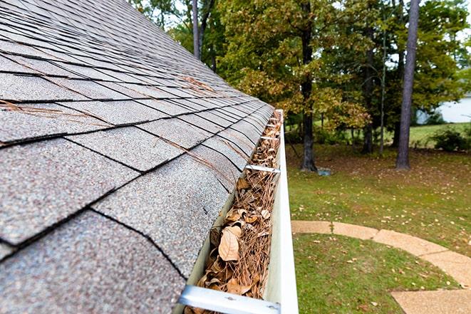 maintenance worker removing leaves from a gutter